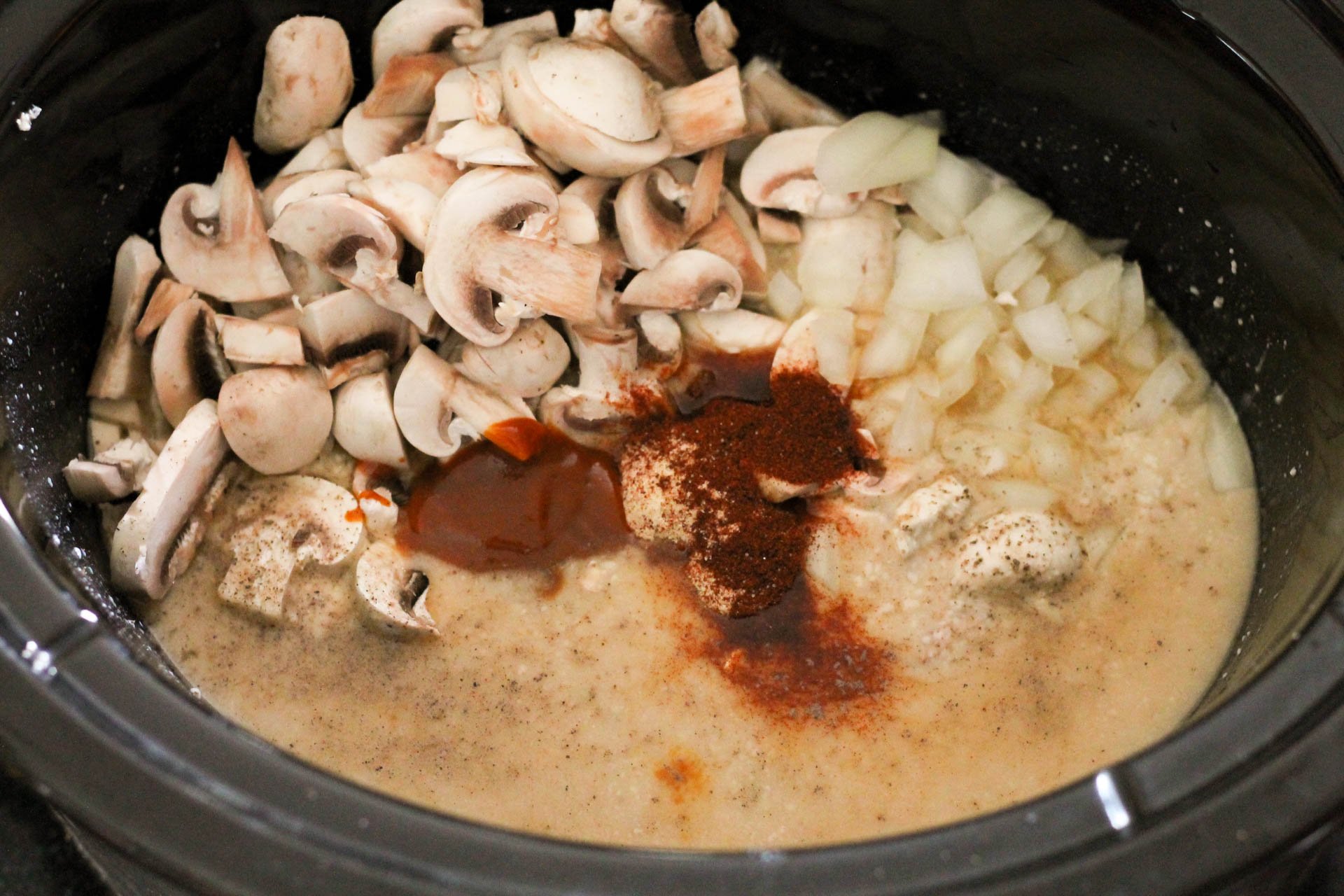 Mushrooms, onion, and spices added to the slow cooker.