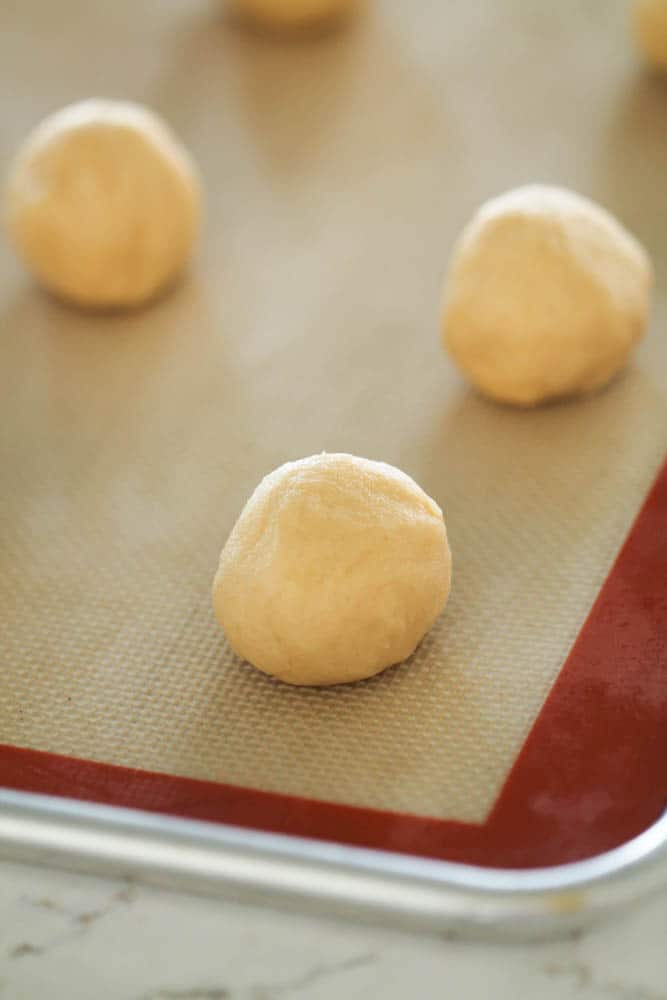 Vanilla Cookie dough balls on a baking sheet with a liner.