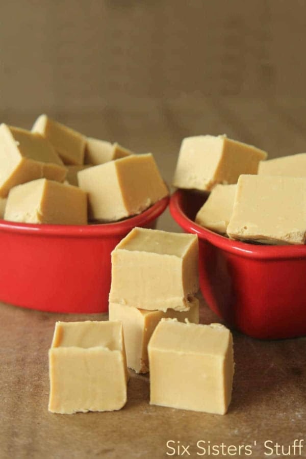 Two red bowls filled with multiple cubes of yellow fudge on a wooden surface.