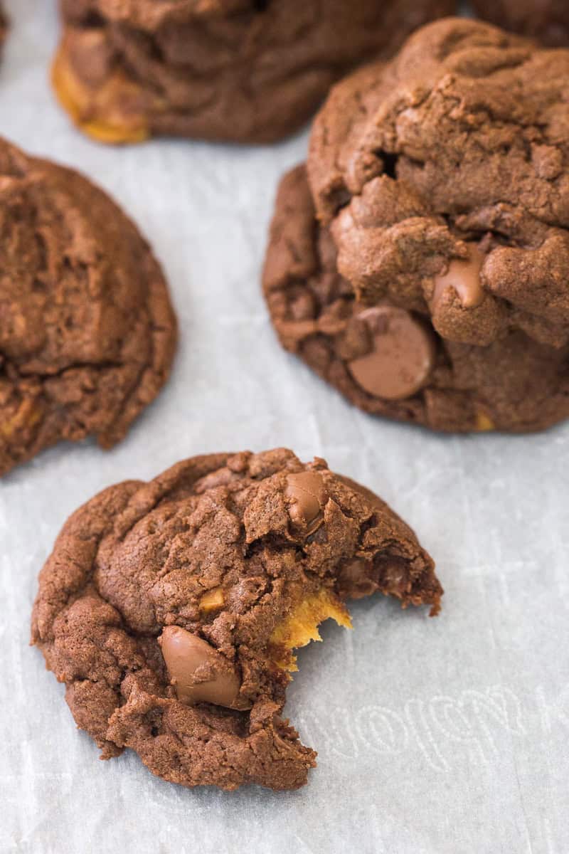 Chocolate Caramel Nutella Cookies on parchment paper with one cookie missing a bite.