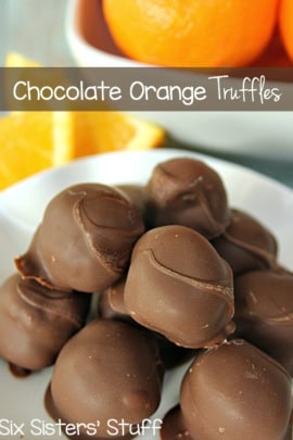 Chocolate Orange Truffles on a white serving plate with fresh oranges and orange slices in the background.