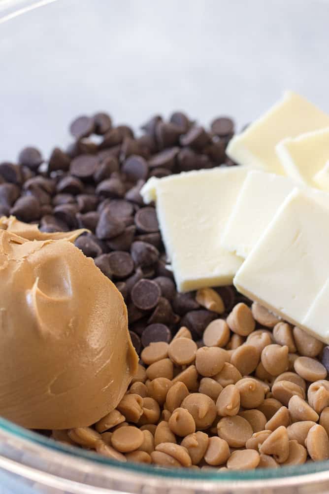 Chocolate chips, butter, and peanut butter in a glass mixing bowl for Chubby Hubby Clusters.