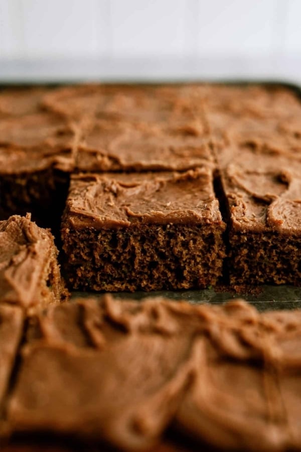 Frosted Chocolate Zucchini Sheet Cake cut into squares in a baking sheet.