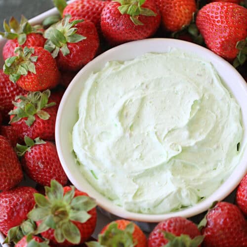 A small bowl of Creamy Pistachio Fruit Dip on a platter with strawberries.