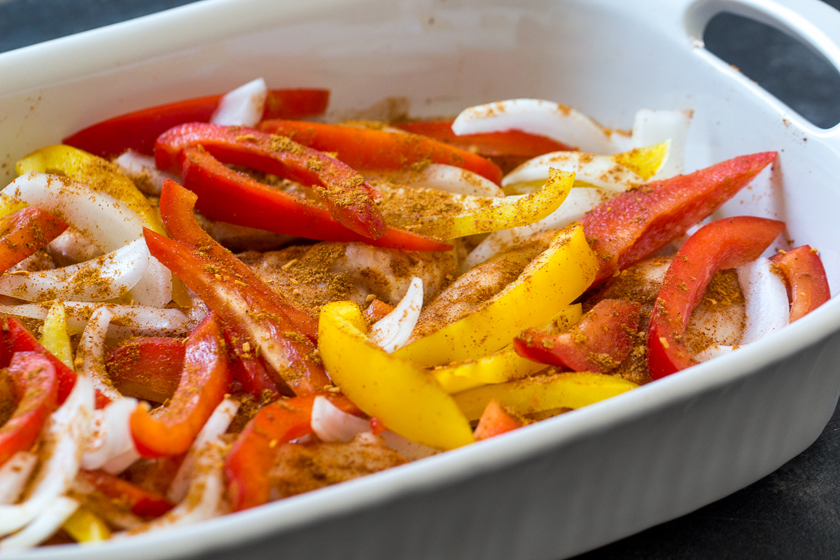 Vegetables layered on top of chicken in pan