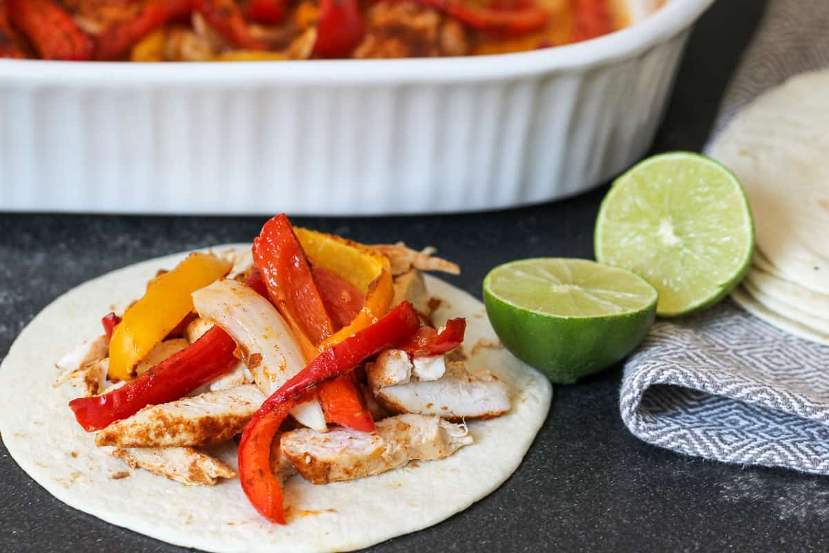 One Pan Baked Fajitas with a tortilla filled with fajitas