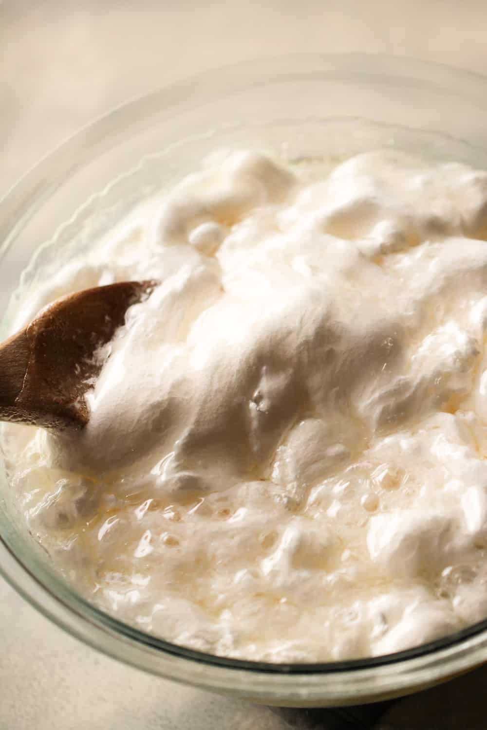Adding sugar and corn syrup mixture to marshmallow creme in mixing bowl