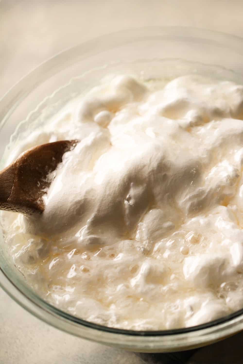 Adding sugar  and corn syrup mixture to marshmallow creme in mixing bowl