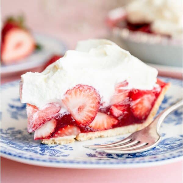 A slice of Fresh Strawberry Pie on a plate with a fork. The remaining pie in the background.