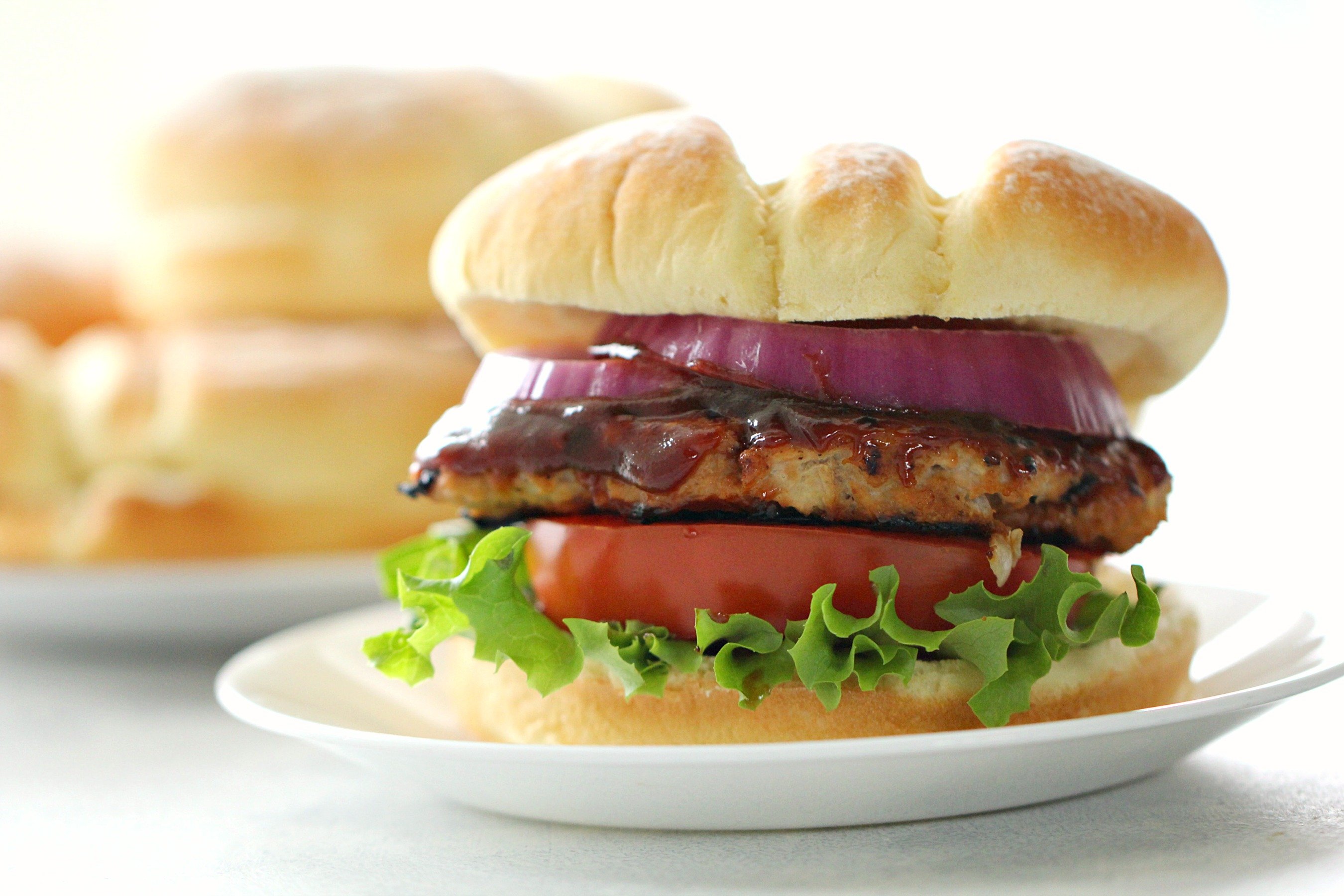 BBQ Turkey Burger with bun and toppings served on a white plate