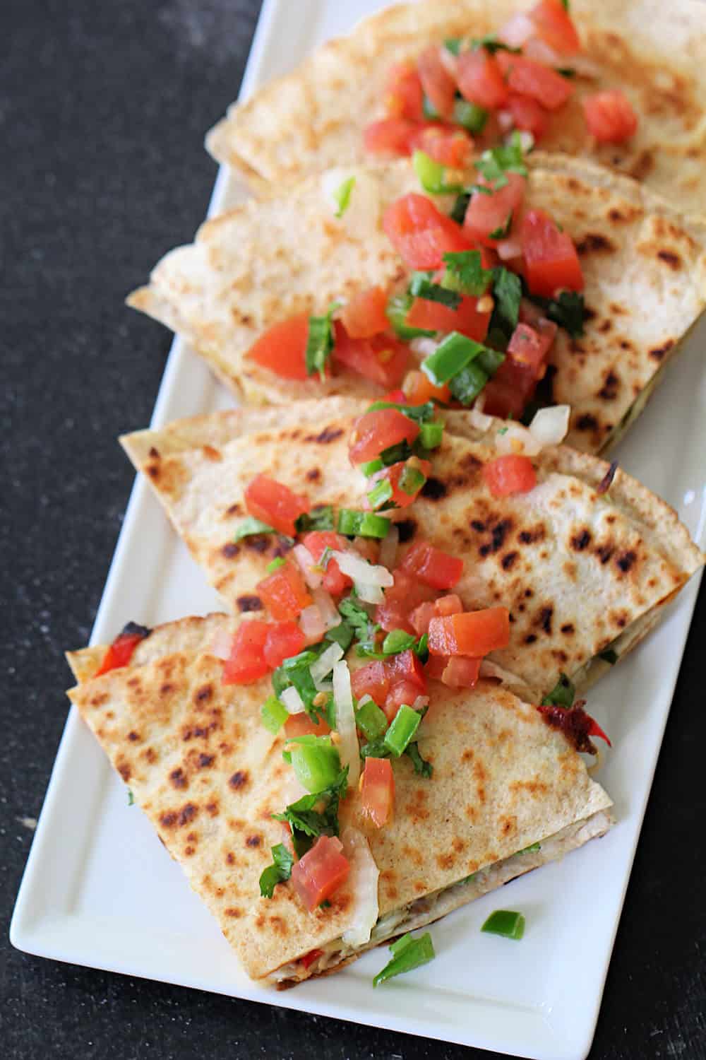 Green Chile and Chicken Quesadillas sliced on a platter topped with salsa