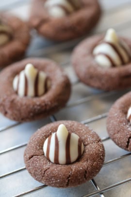 Chocolate cookies topped with striped white and milk chocolate pieces, cooling on a wire rack.