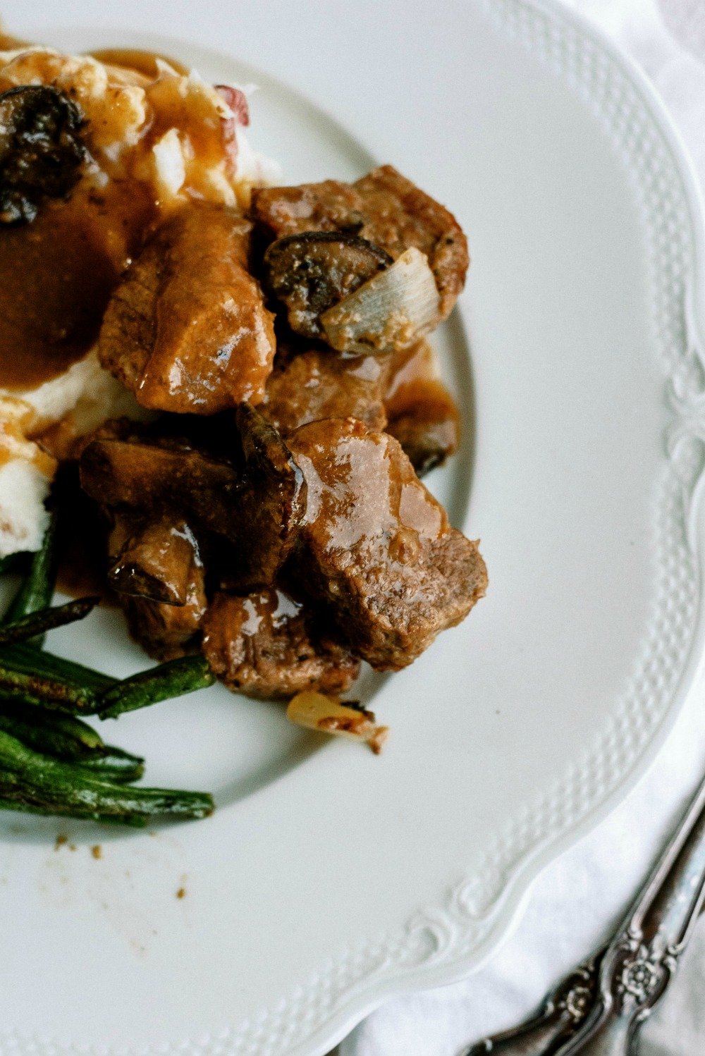 Slow Cooker Beef Sirloin Tips and Gravy on a white plate served with green beans and mashed potatoes