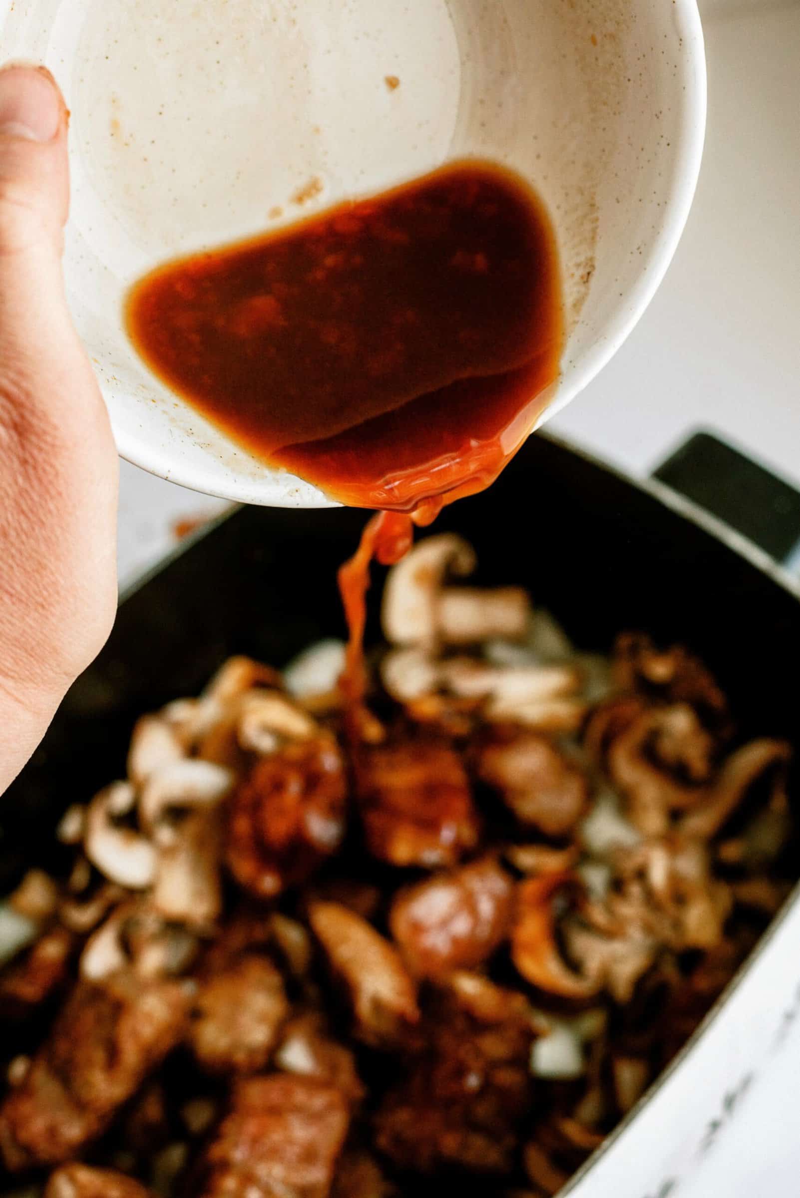 Pouring broth mixture on top of beef tips