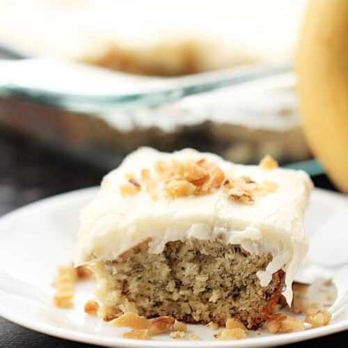 A slice of Frosted Banana Cake Recipe on a white plate.