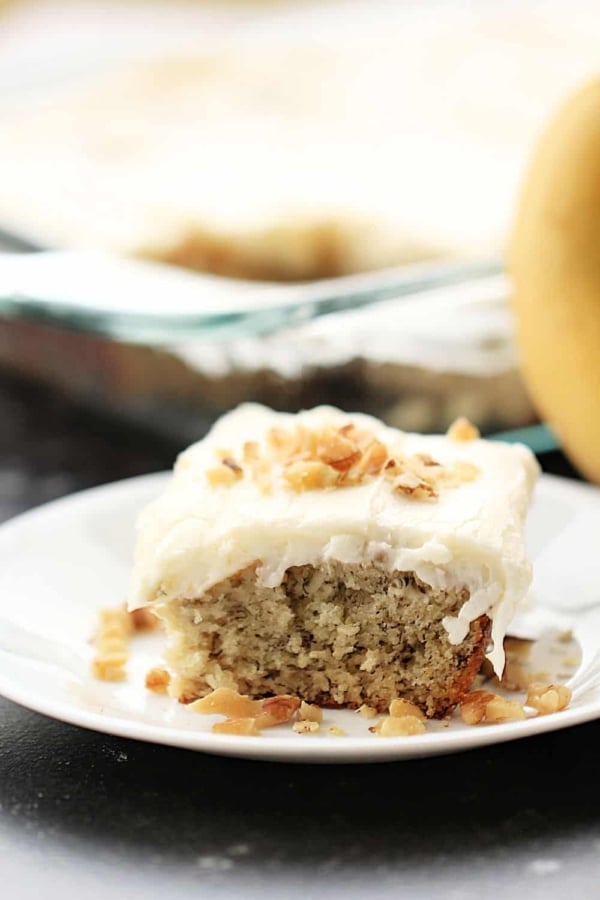 A slice of Frosted Banana Cake Recipe on a white plate.