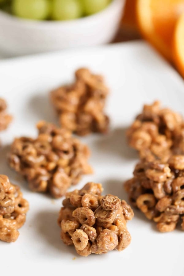 Close-up of a white plate holding several clusters of cereal and melted marshmallows, peanut butter breakfast bites