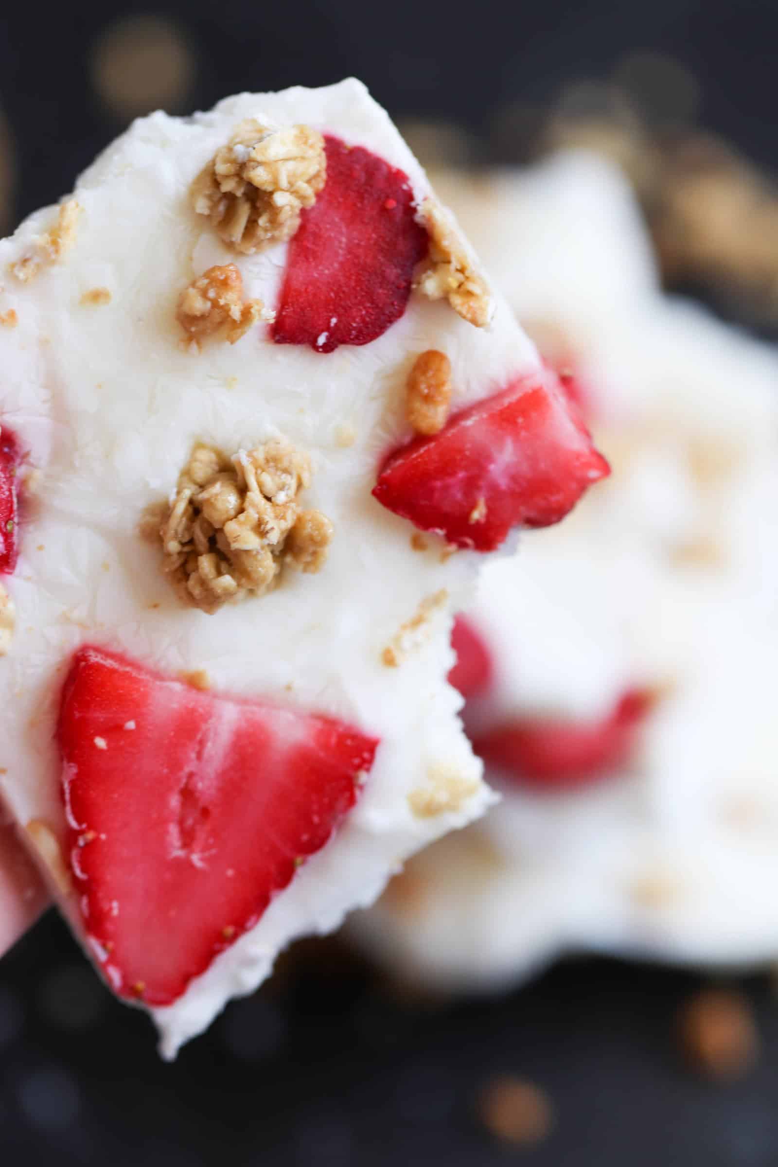 A square of Strawberry Granola Yogurt Bark with a bite missing.
