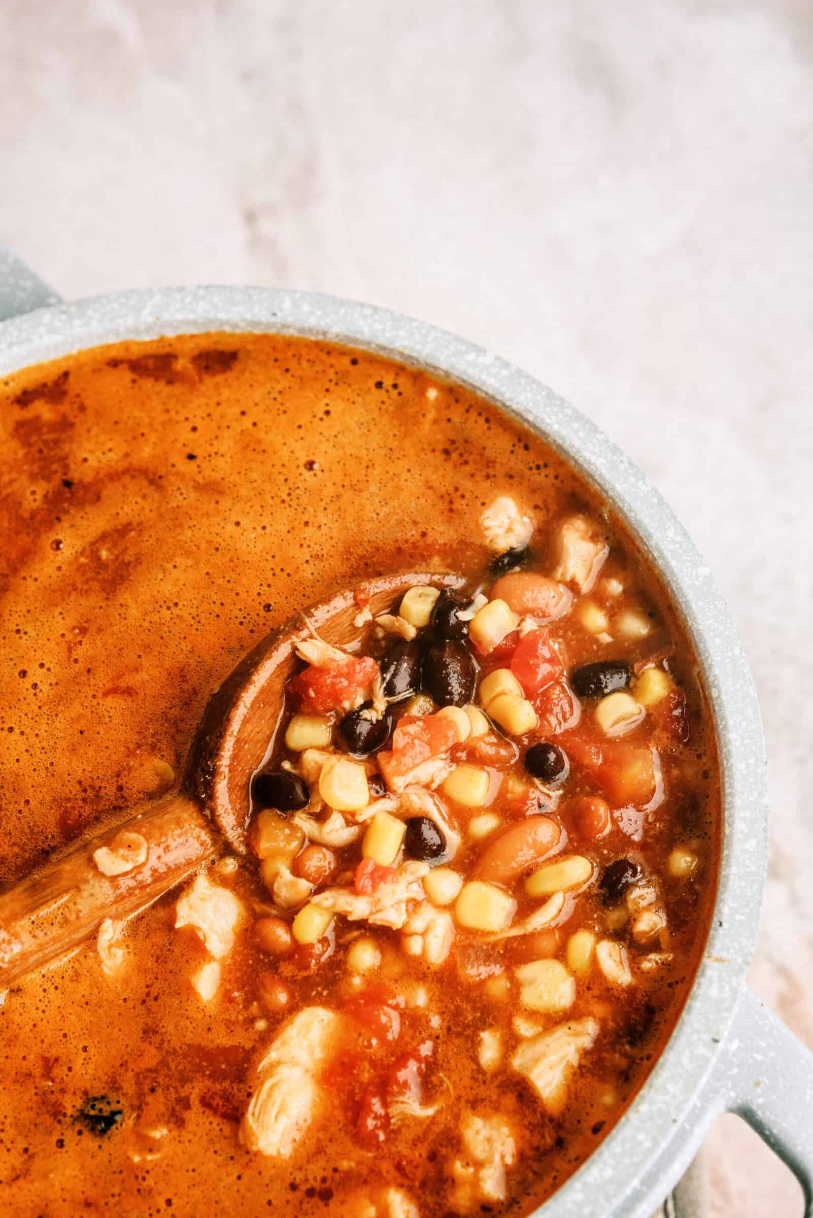 Seven Can Chicken Tortilla Soup in large stock pot with a wooden spoon