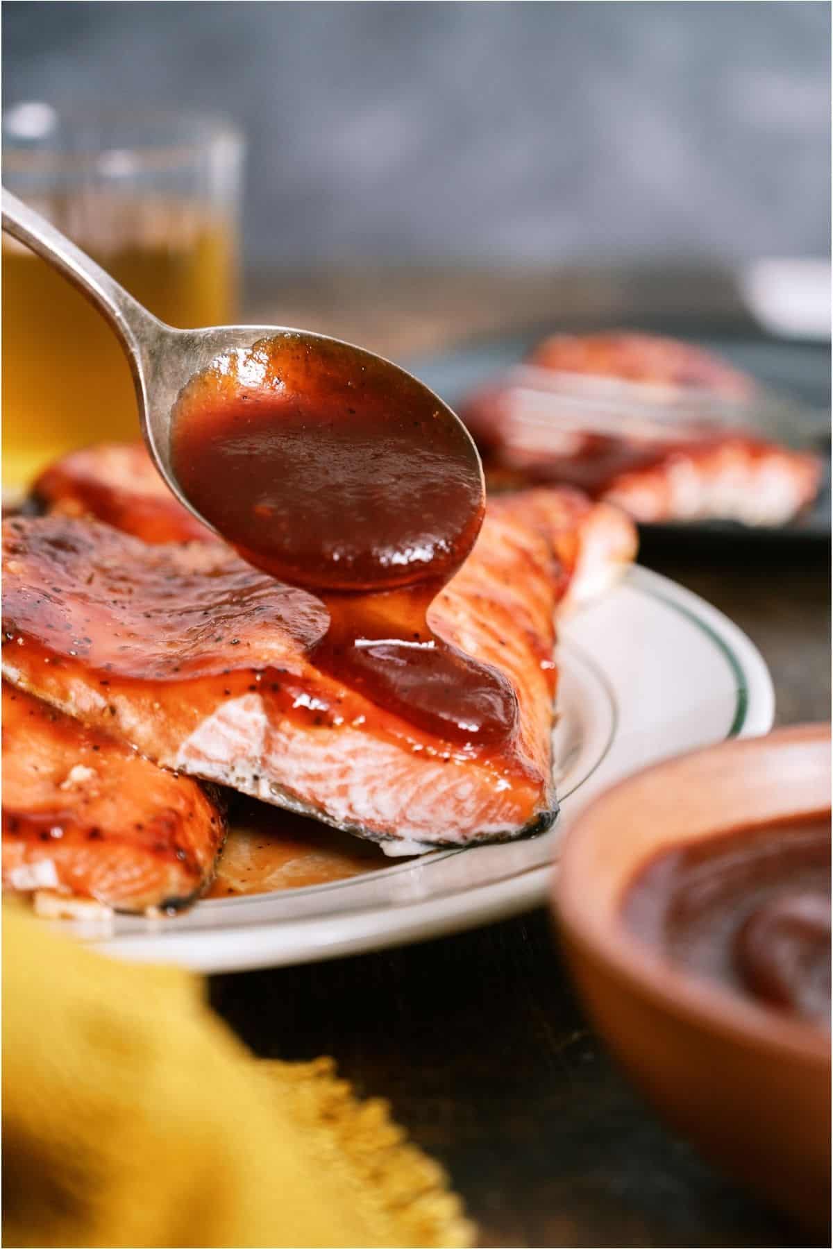Spooning BBQ sauce on top of salmon.