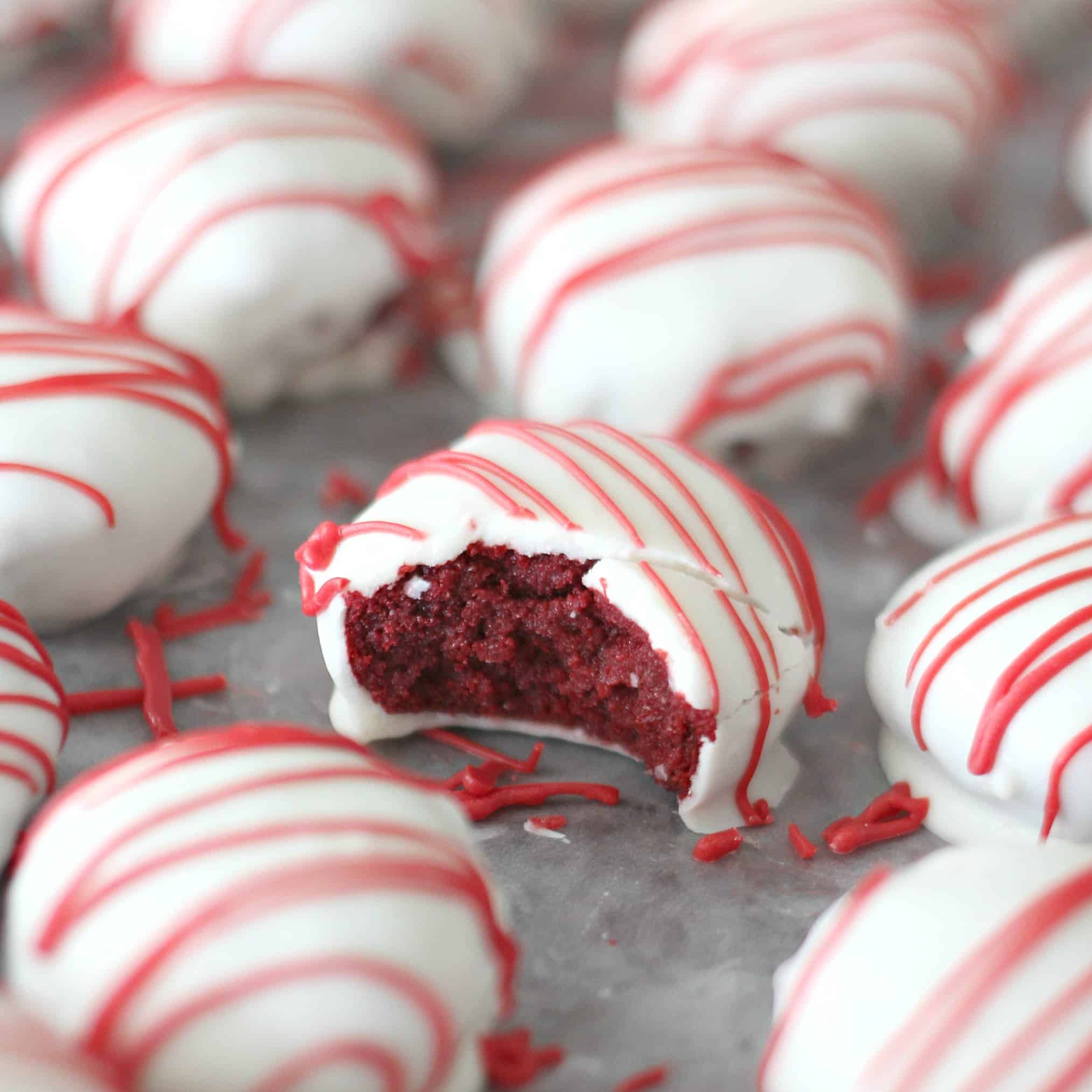 Red Velvet Cake Bites lined up in rows with one missing a bite to show the insides of it.