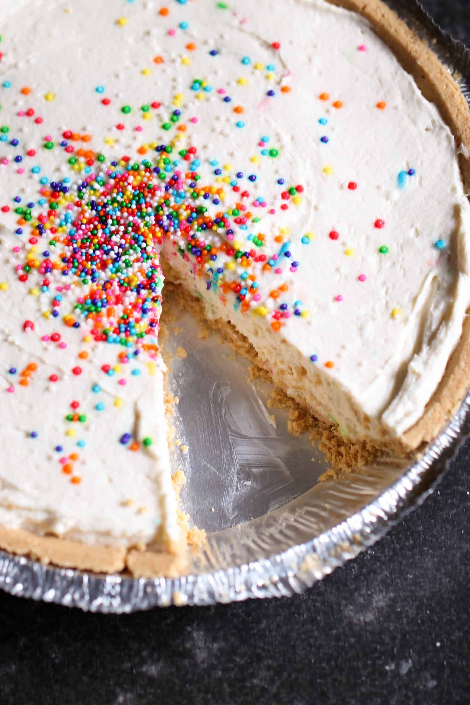 5-Ingredient Cake Batter Cheesecake with sprinkles missing a piece
