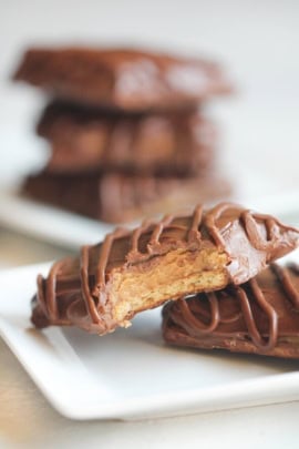 Disneyland chocolate peanut butter sandwich on a plate with a bite taken out of it. Other cookies in the background.