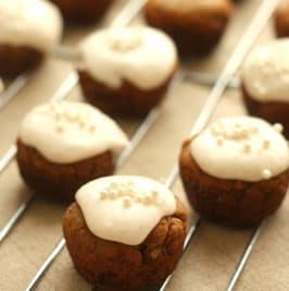 Small round cookies topped with white icing and sprinkles, arranged on a wire rack.
