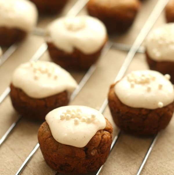 Small round cookies topped with white icing and sprinkles, arranged on a wire rack.