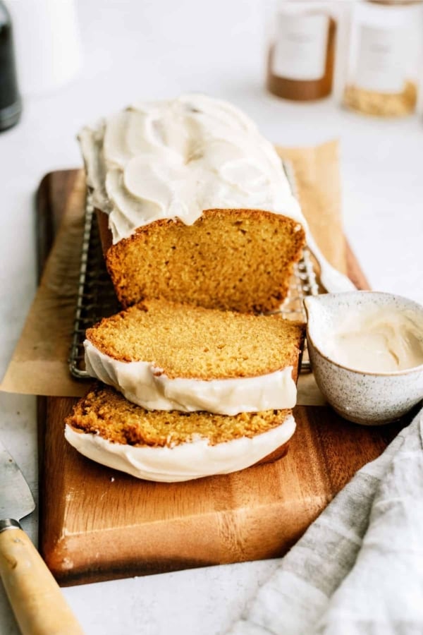 pumpkin bread with maple glaze sliced on wood cutting board