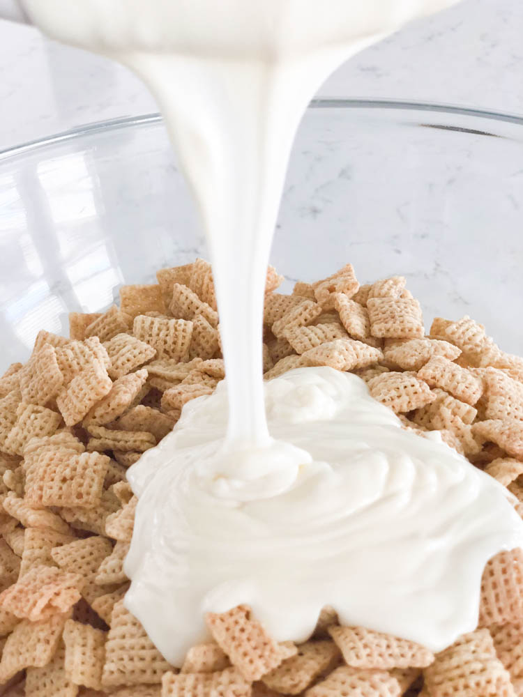 melted white chocolate being poured on cinnamon chex mix