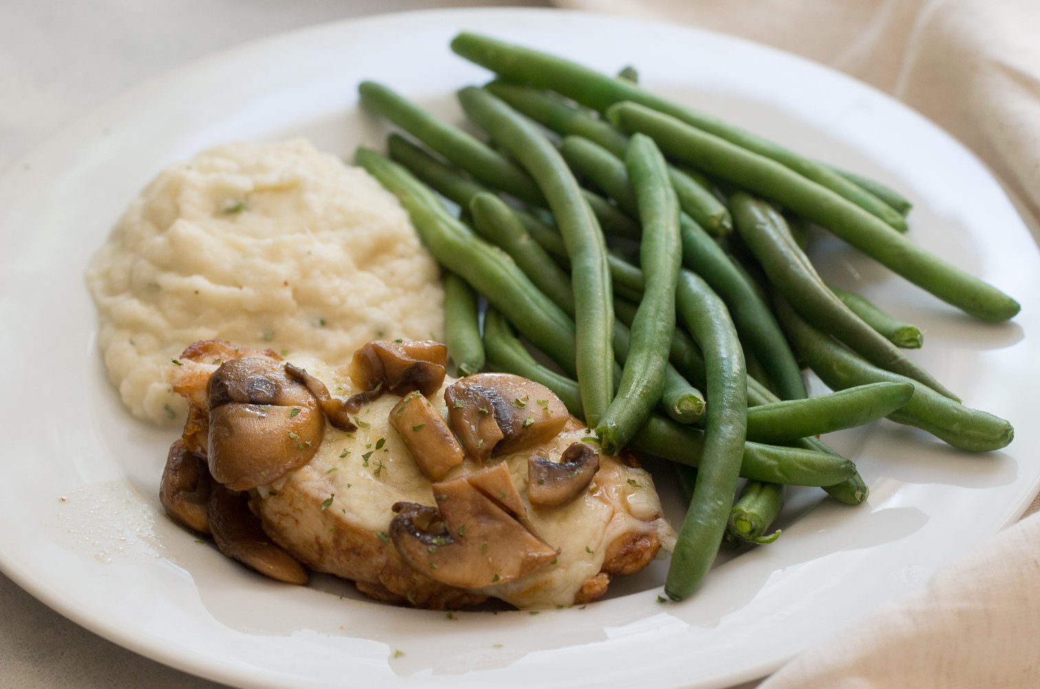 Copycat Cheesecake Factory Chicken Madeira on a plate with green beans and mashed potatoes