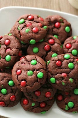 A plate of chocolate cookies topped with red and green candy-coated chocolates.