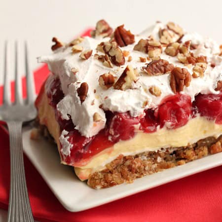 A slice of Layered Cherry Cheesecake Lush on a plate with a fork.