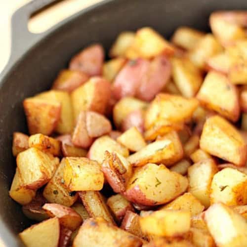 Diced and seasoned roasted potatoes in a black cast iron skillet.