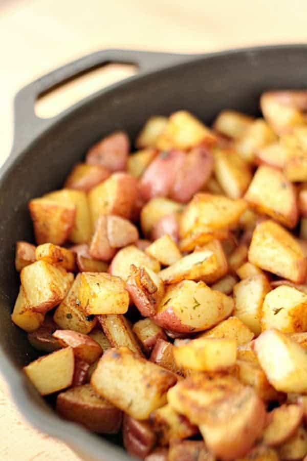 Diced and seasoned roasted potatoes in a black cast iron skillet.