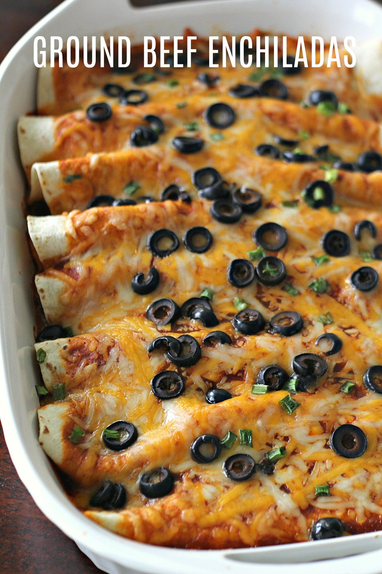 ground beef enchiladas in baking dish with olives and cheese