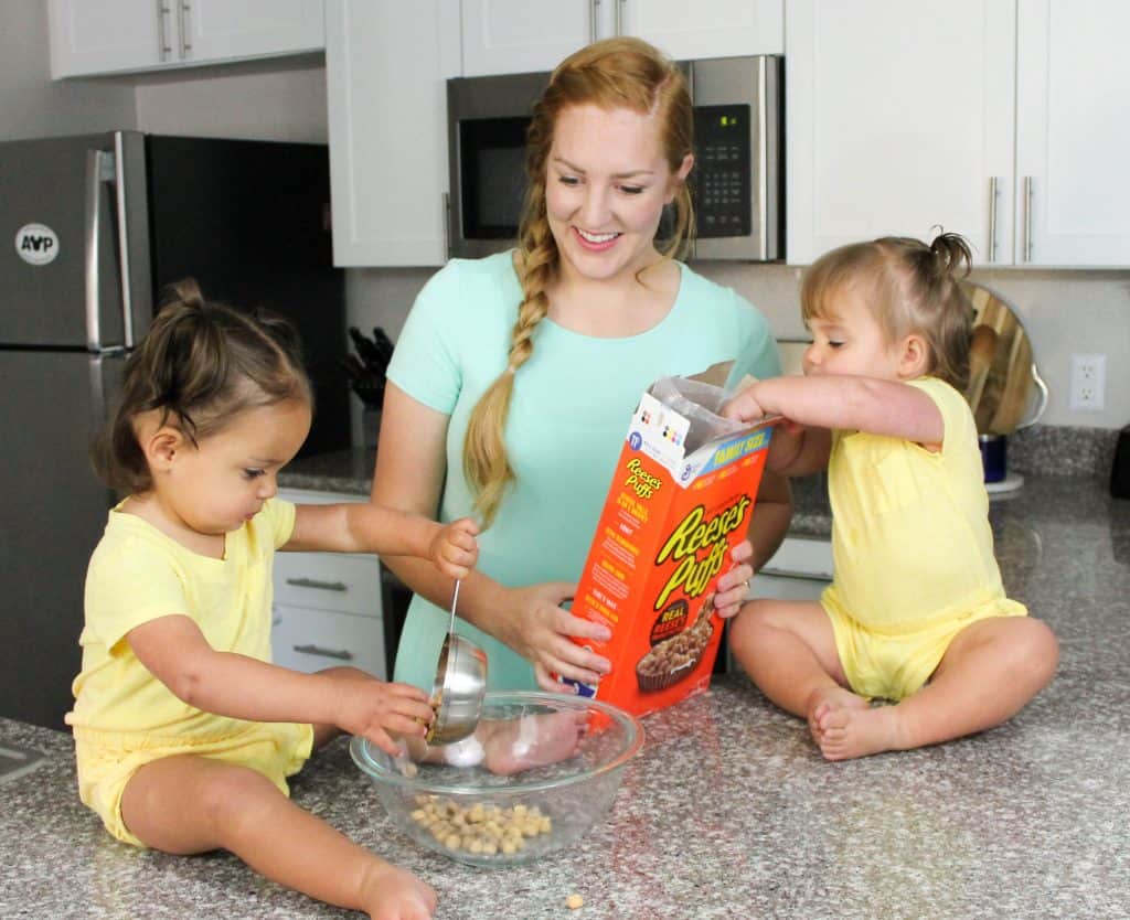 Mom and 2 babies with a box of Reese's Puffs