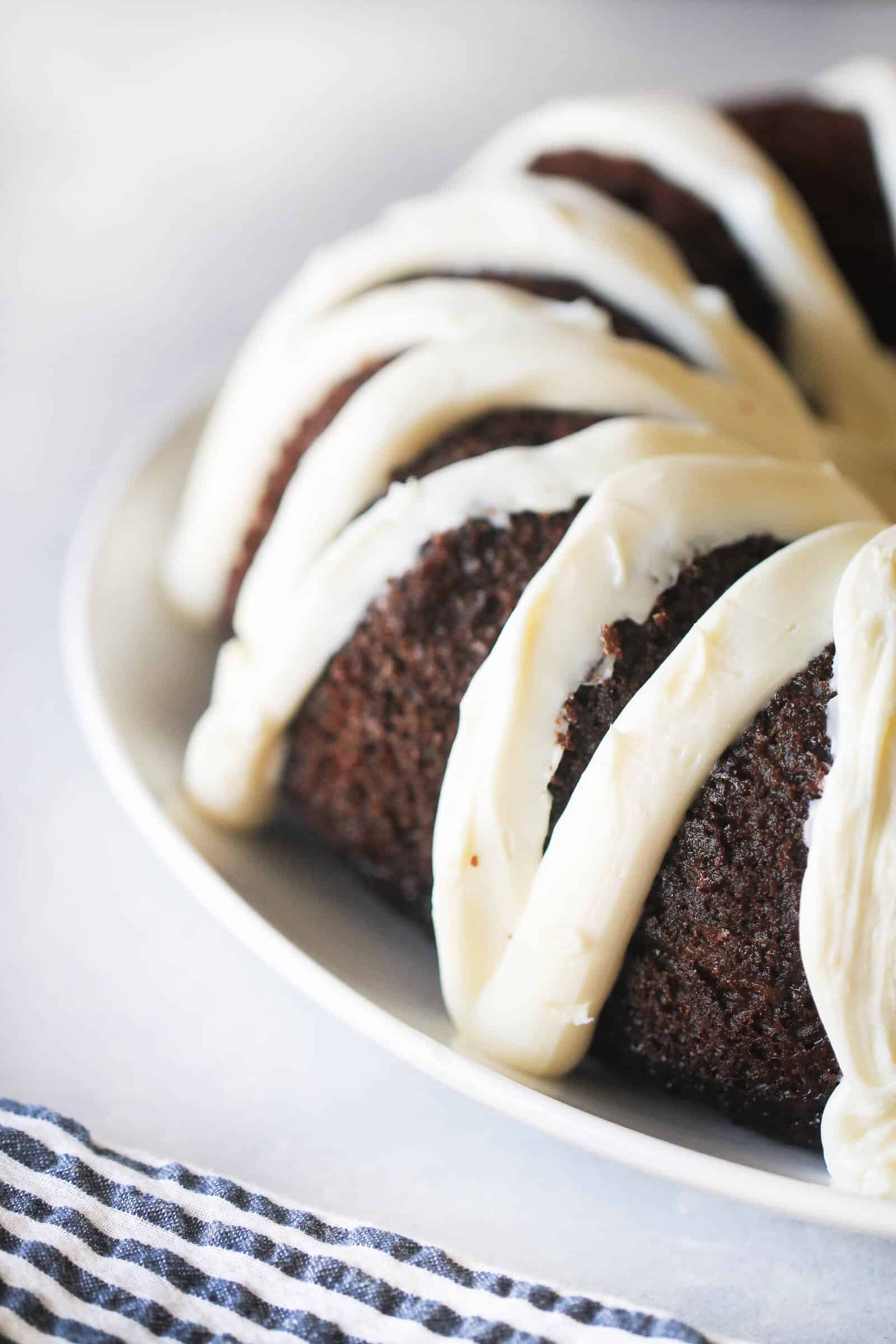 Chocolate Zucchini Cake topped with frosting on a serving platter