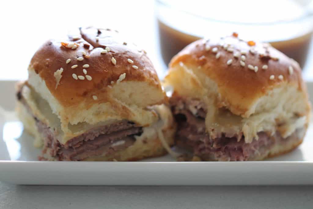 2 French dip sliders on a white plate.