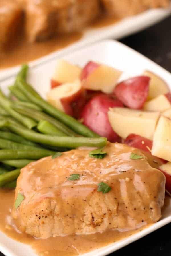 Apple Cider Pork Chop on a plate with a side of potatoes and green beans