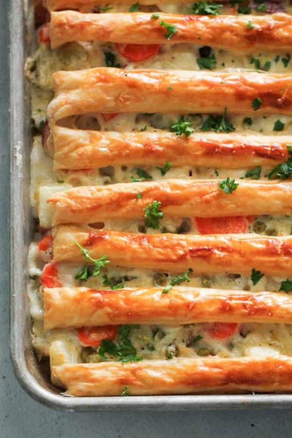 Rectangular dish filled with a baked, layered pastry topped with cheese, herbs, and carrots.