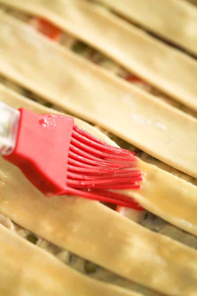 Pastry brush brushing egg wash on pastry strips