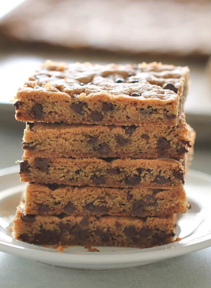 Sliced Sheet Pan Chocolate Chip Cookie Bars stacked on a white plate
