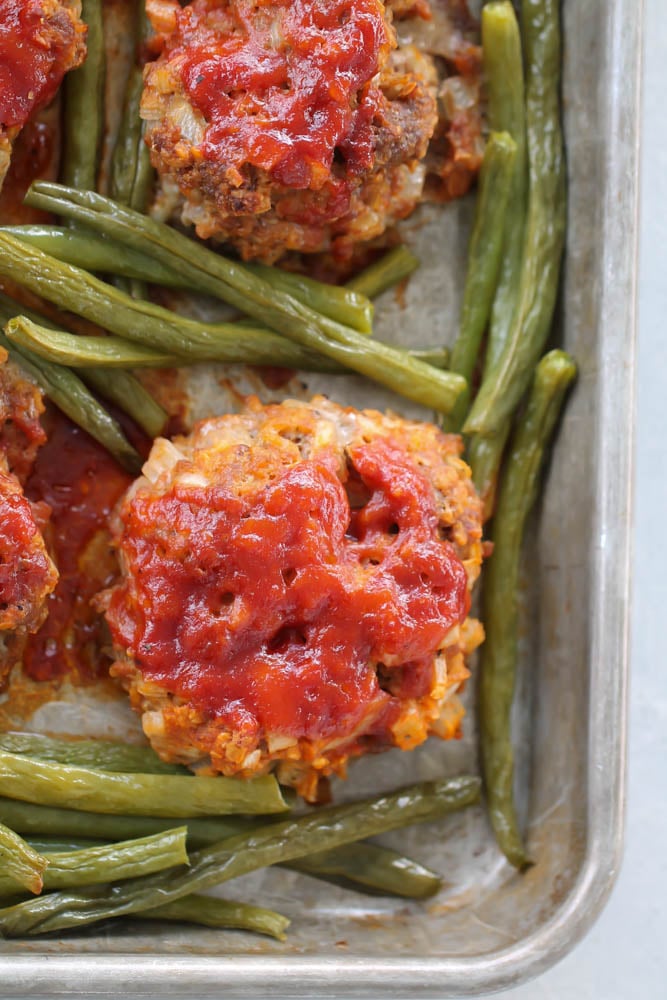 Meatloaf patties and green beans on a sheetpan.