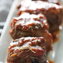 Close-up of glazed slow cooker short ribs garnished with herbs on a white platter.