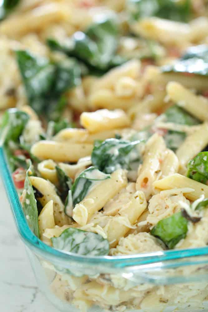 chicken casserole with pasta and pesto in glass baking dish