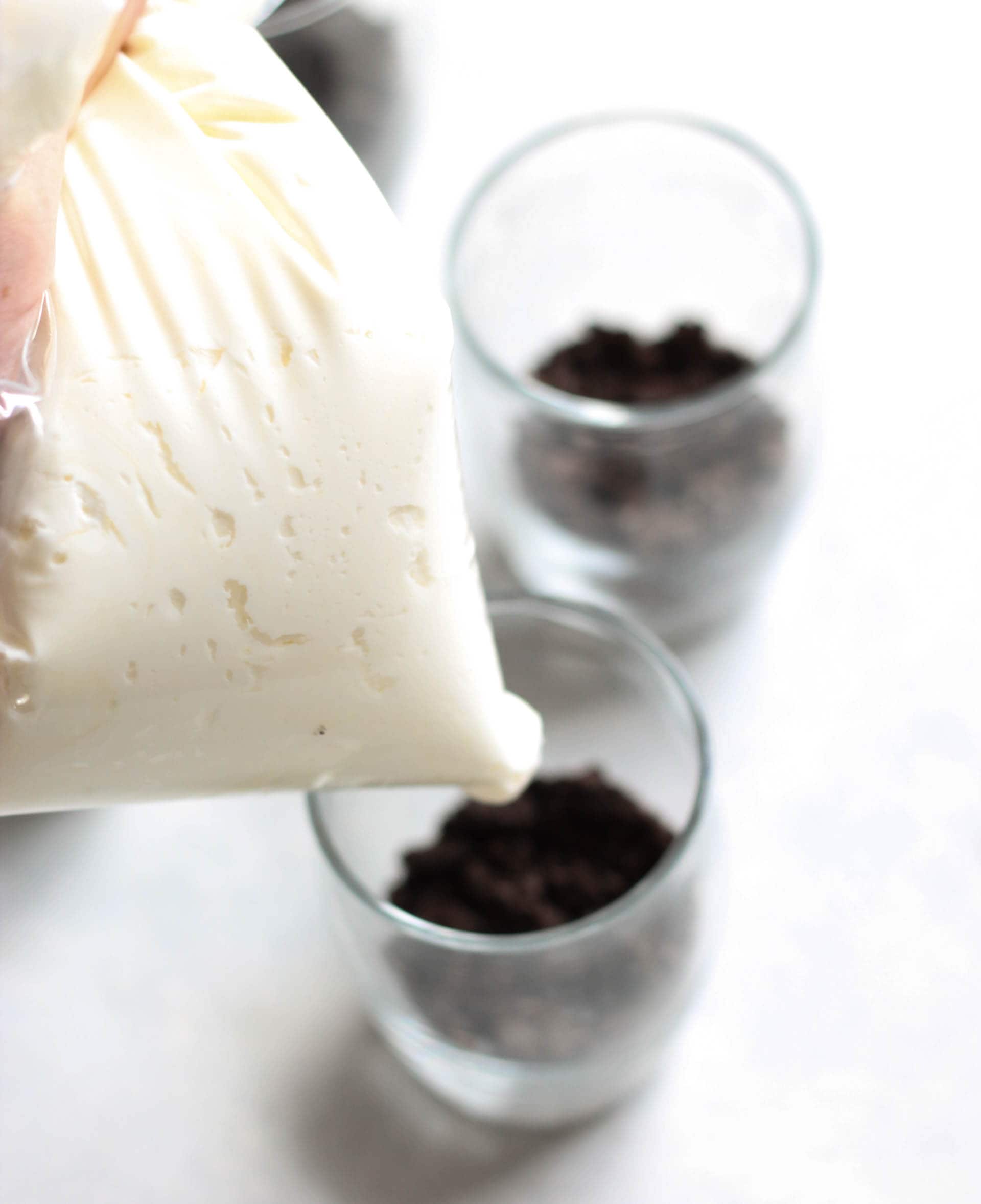 Piping cheesecake mixture on top of oreo crust