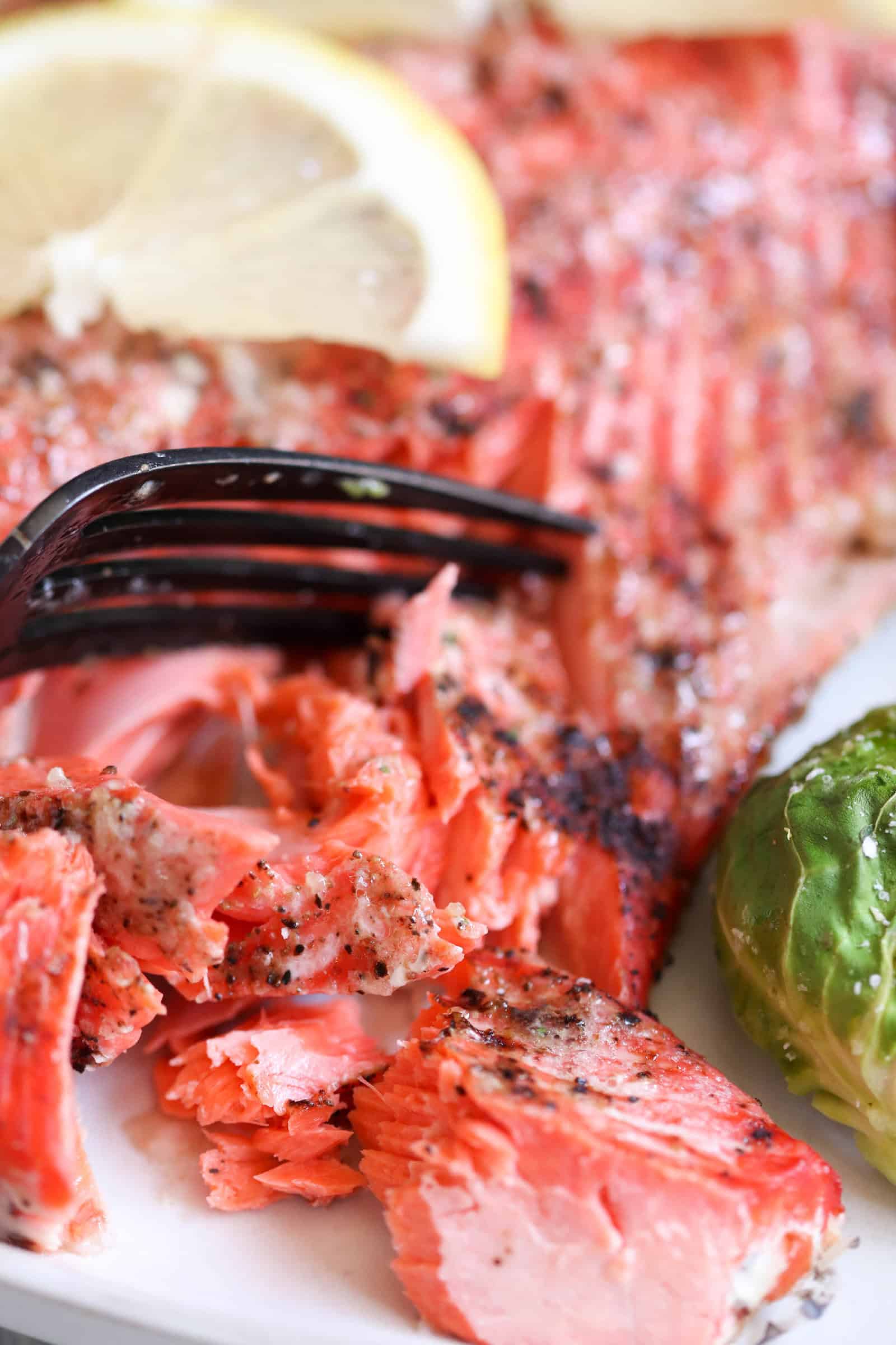 A fork with flaked salmon topped with lemon on a plate