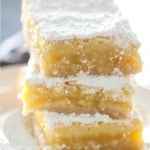 Lemon Bars stacked on plate topped with powdered sugar.